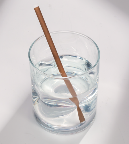 6-inch natural brown compostable hemp straw in a short glass of water